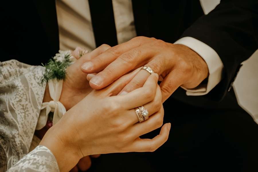 A close-up shot of a groom placing a ring on the bride's finger during a ceremony, the culmination of careful Wedding Planning.